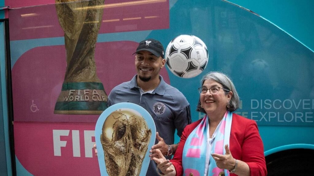 Miami Dade County Mayor, Daniella Levine Cava, right, and Inter Miami’s Gregore pose for photos in front of the 2026 FIFA World Cup logo.