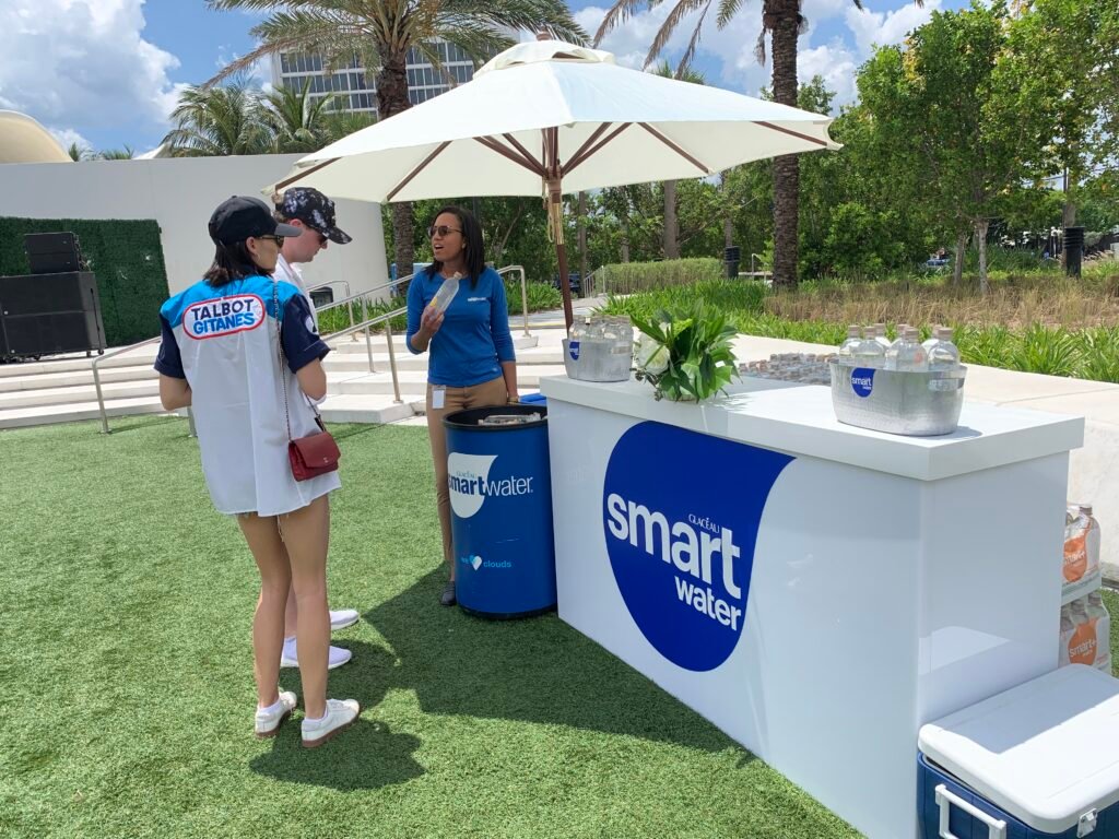 Smartwater brand ambassador engaging attendees and offering samples.